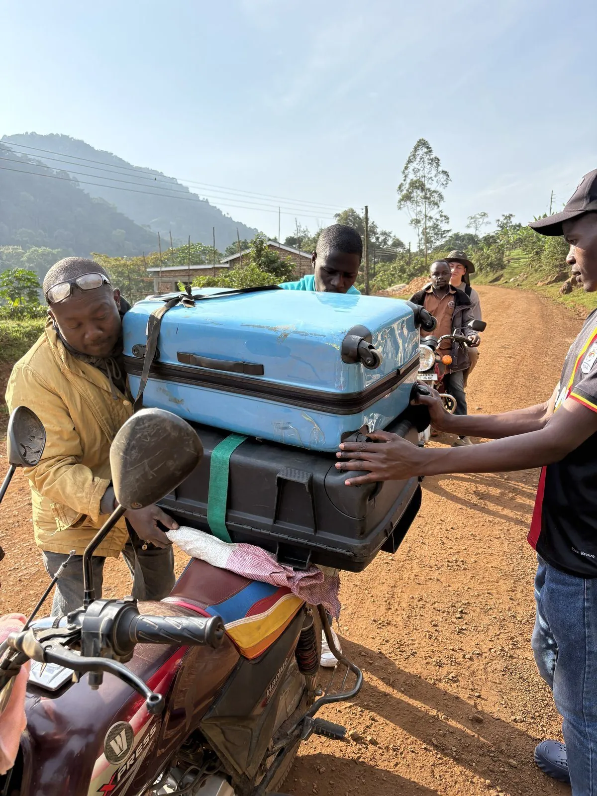Bodaboda-Fahrer transportiert Koffer auf dem Motorrad in Bwindi Uganda — lokaler Transport am Nationalpark